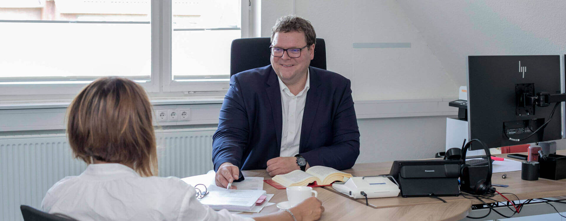 Steuerberater Christian Lübbers sitzt am Tisch mit weiterer Person