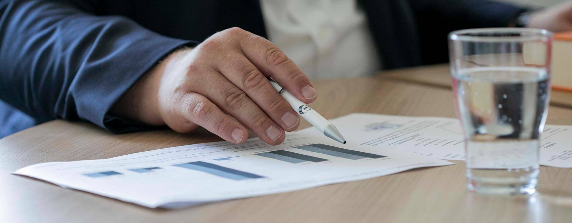 Steuerberater zeigt mit Stift auf Statistiken